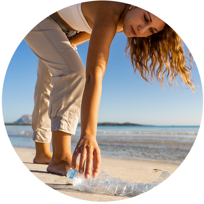 Nainen kerää muovipullon rannasta