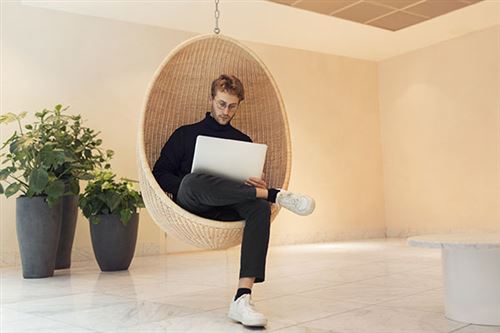 Nuori mies istuu korituolissa tietokone sylissä.