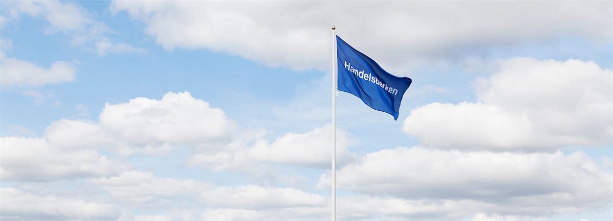 Handelsbankenin lippu salossa sinivalkoista taivasta vasten.