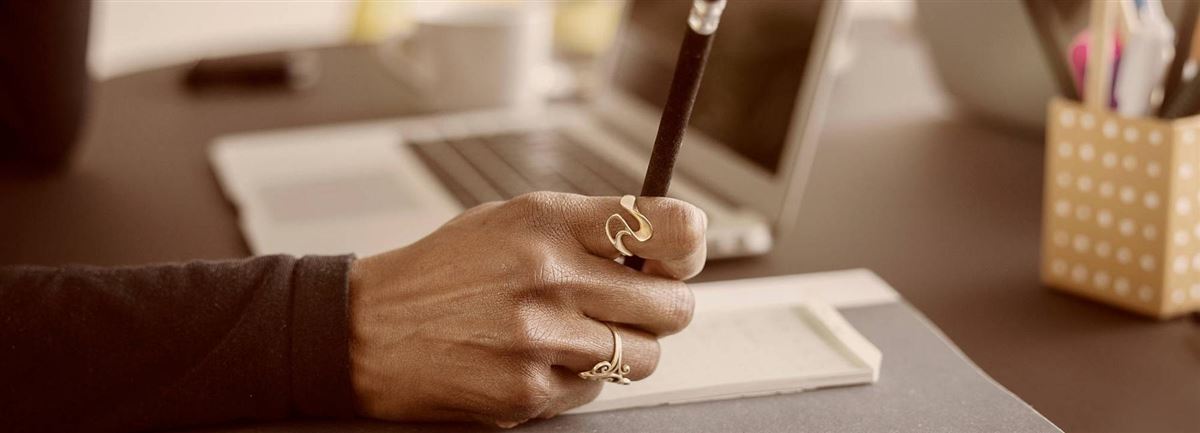 Käsi työpöydällä kirjoittamassa