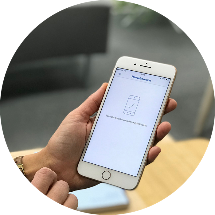 Puhelin kädessä ja Vahvista-sovellus auki.