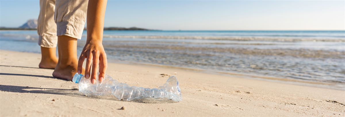 Kvinna samlar in plastskräp på stranden