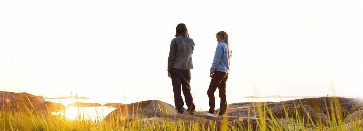 Två unga tittar på solnedgången på stranden.