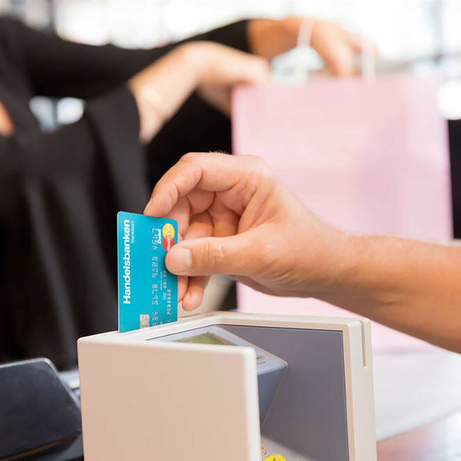 Kundens hand och kreditkort vid betalterminalen