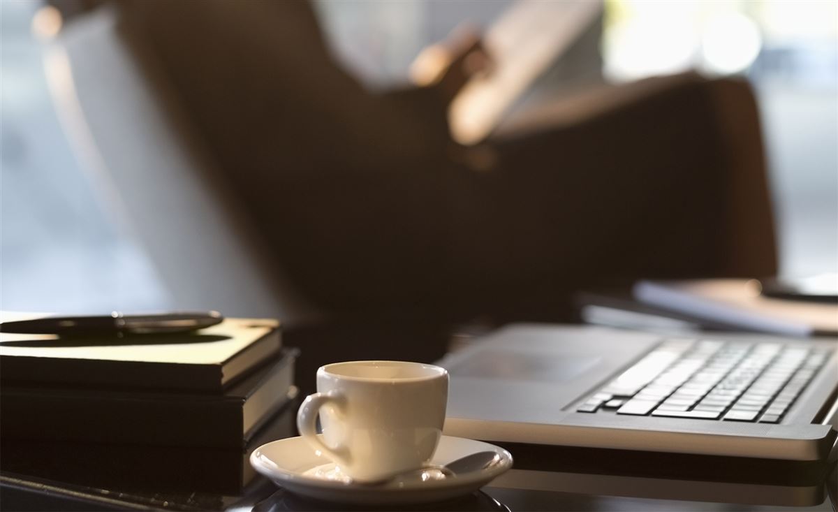 En kaffekopp står bredvid en bärbar dator.