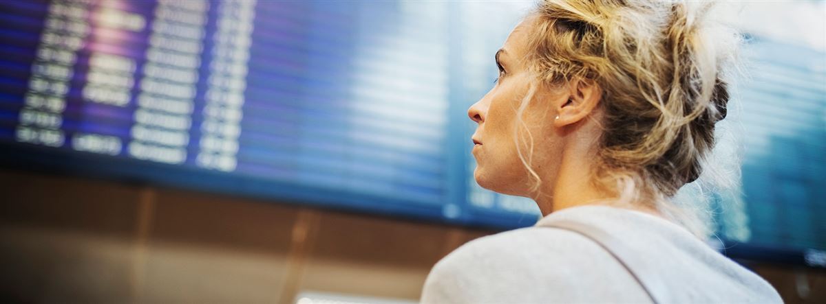 En kvinna tittar på informationstavlan för utgående flyg.