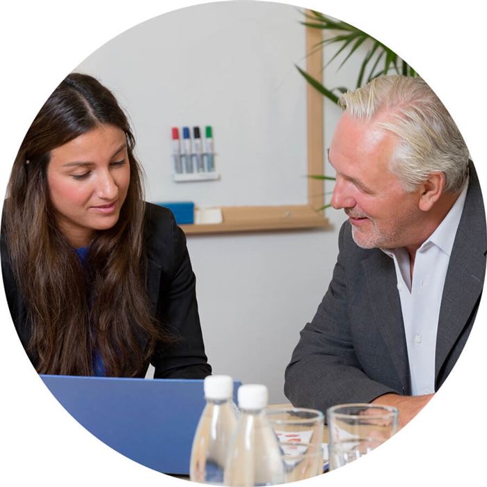 En kvinna och en man diskuterar samtidigt som de tittar på datorskärmen.